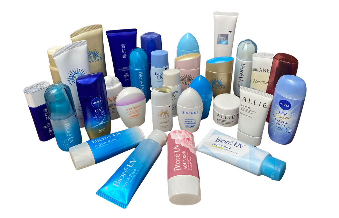 Assorted sunscreen and skincare tubes and bottles arranged in a group on a black background, displaying various brands and SPF products.