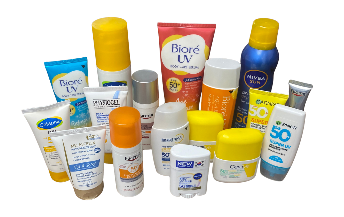 Group of assorted sunscreen bottles and tubes from brands like Biore, Nivea, Garnier, Cetaphil on a black background.